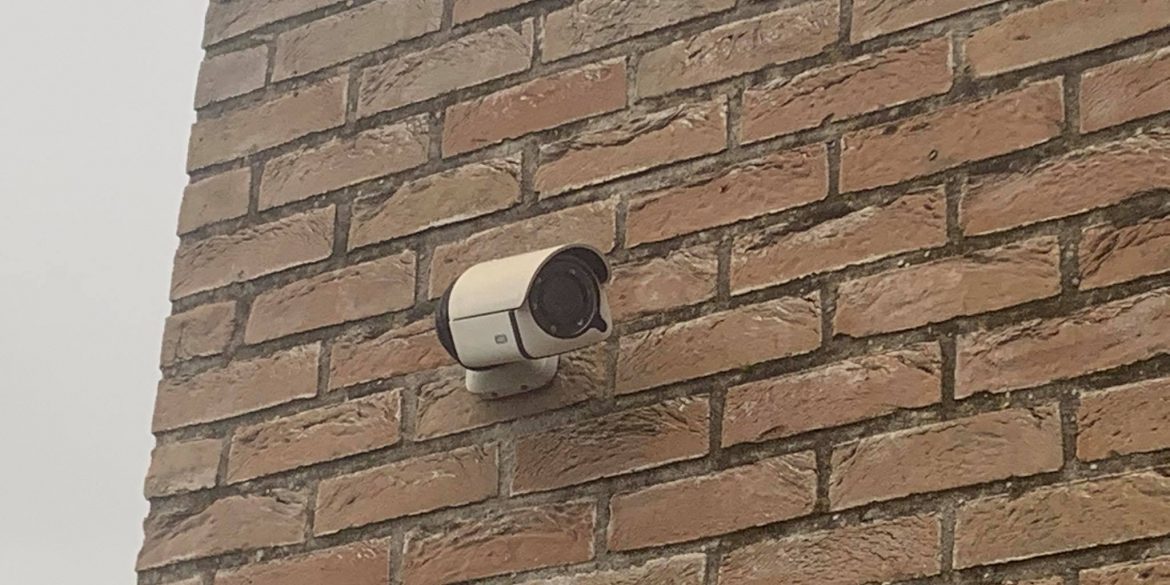 een camera hangt aan een bakstenen muur