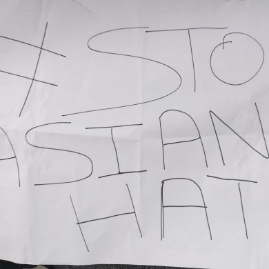 Twee handen houden een papier vast waar #StopAsianHate op staat