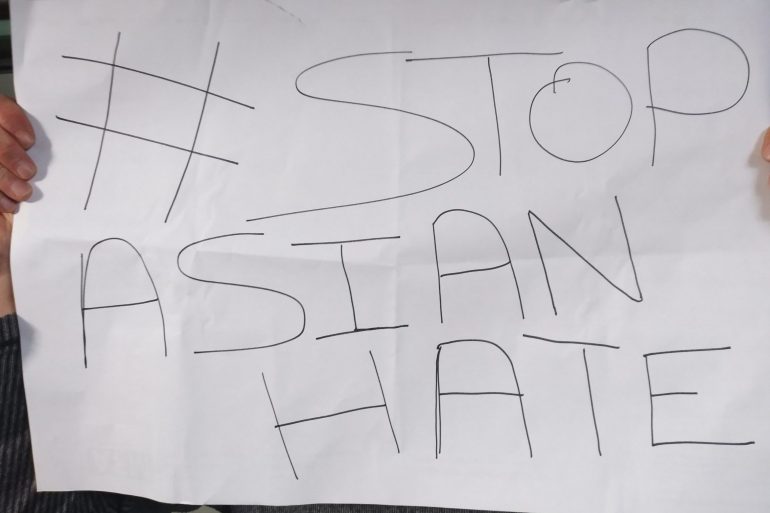 Twee handen houden een papier vast waar #StopAsianHate op staat
