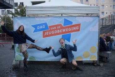 2 goedlachse jongeren die poseren voor een doek "Dag van de jeugdbeweging"