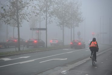 Auto's en fietsers rijden in een mistige straat