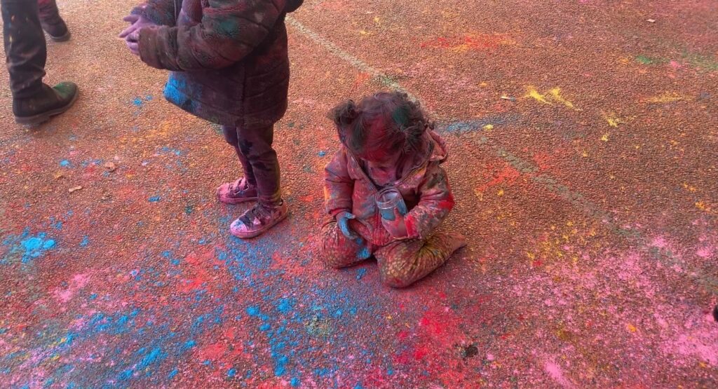 Kind met kleurenpoeder op Holifeest dat op de grond zit. (Foto: Melda Tokgoz) 