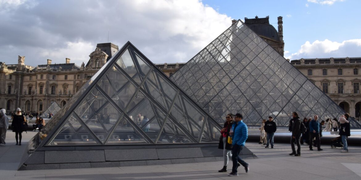 Foto van het Louvre in Parijs, twee glazen piramides, voorbijgangers