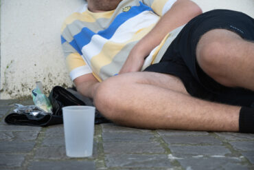 een dakloze jonge die op straat ligt met rolsigaretten.