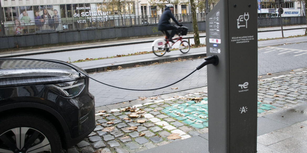 Een auto is langs de kant van de weg geparkeerd om op te laden aan een laadpaal.