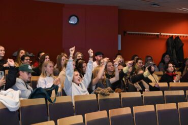 Foto van juichende studenten in een aula