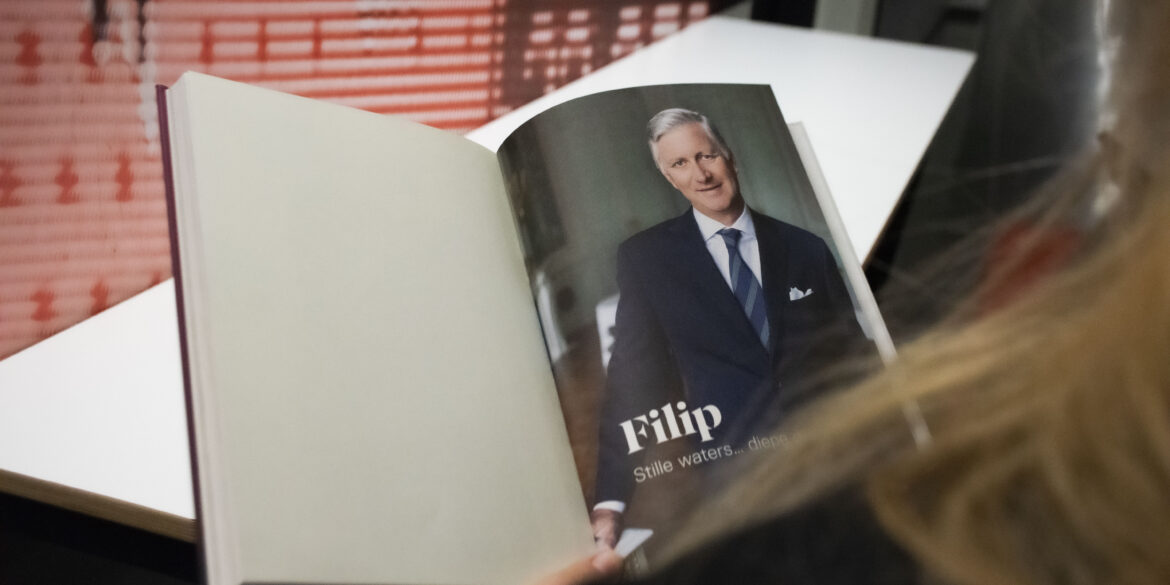 Je kijkt mee over de schouder van een vrouw die een boek leest over koning Filip.