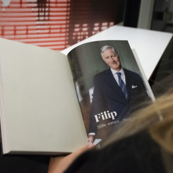 Je kijkt mee over de schouder van een vrouw die een boek leest over koning Filip.