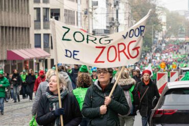 Mensen lopen door Brusselse straten met een spandoek