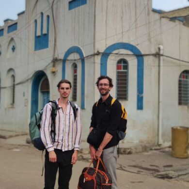 Senne en Joran staan samen in beeld met hun rugzakken op de schouder in Bagdad.