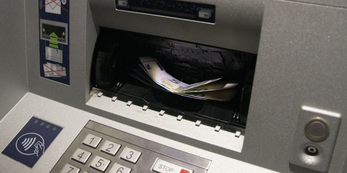 Er liggen geldbriefjes in de gleuf van een bankautomaat.