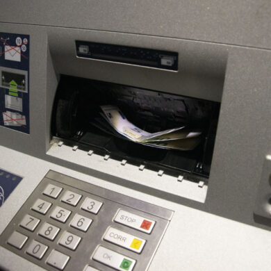 Er liggen geldbriefjes in de gleuf van een bankautomaat.
