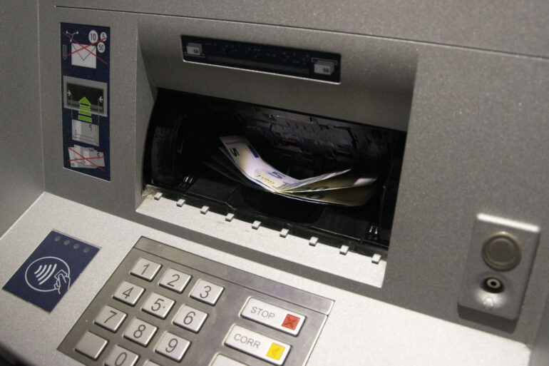 Er liggen geldbriefjes in de gleuf van een bankautomaat.