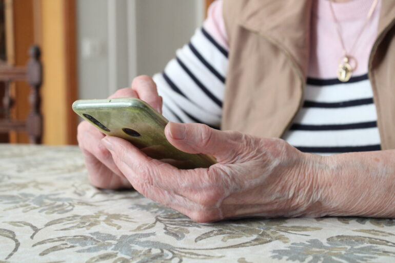 oude vrouw met gsm in haar hand