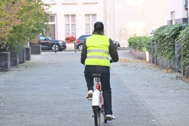 Een fietser met een fluohesje in het verkeer