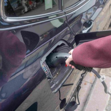 Persoon steekt laadkabel in de auto.