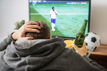 Persoon die voetbal kijkt op zijn TV