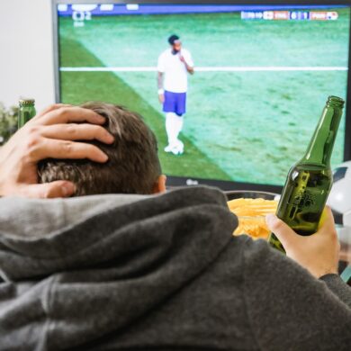 Persoon die voetbal kijkt op zijn TV