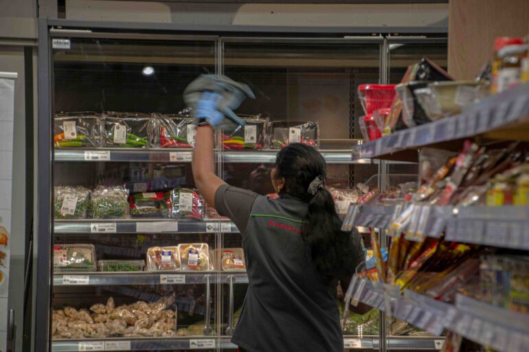 werknemer in een supermarkt dat ruiten poetst
