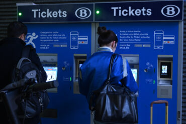 Mensen kopen een ticket aan een ticketautomaat van de NMBS