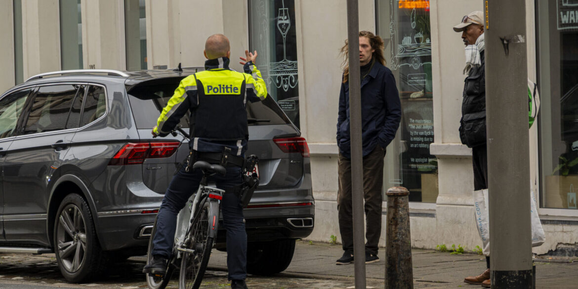 Politieagent op fiets spreekt man aan.