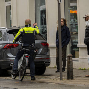 Politieagent op fiets spreekt man aan.
