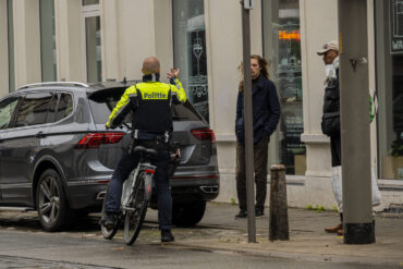 Politieagent op fiets spreekt man aan.