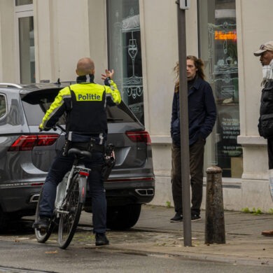 Politieagent op fiets spreekt man aan.