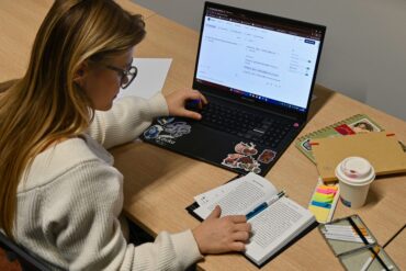 Een vertaler aan het werk met een open boek en een laptop waarop DeepL een tekst naar het Japans vertaalt.