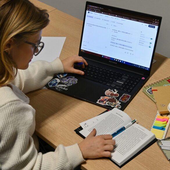 Een vertaler aan het werk met een open boek en een laptop waarop DeepL een tekst naar het Japans vertaalt.